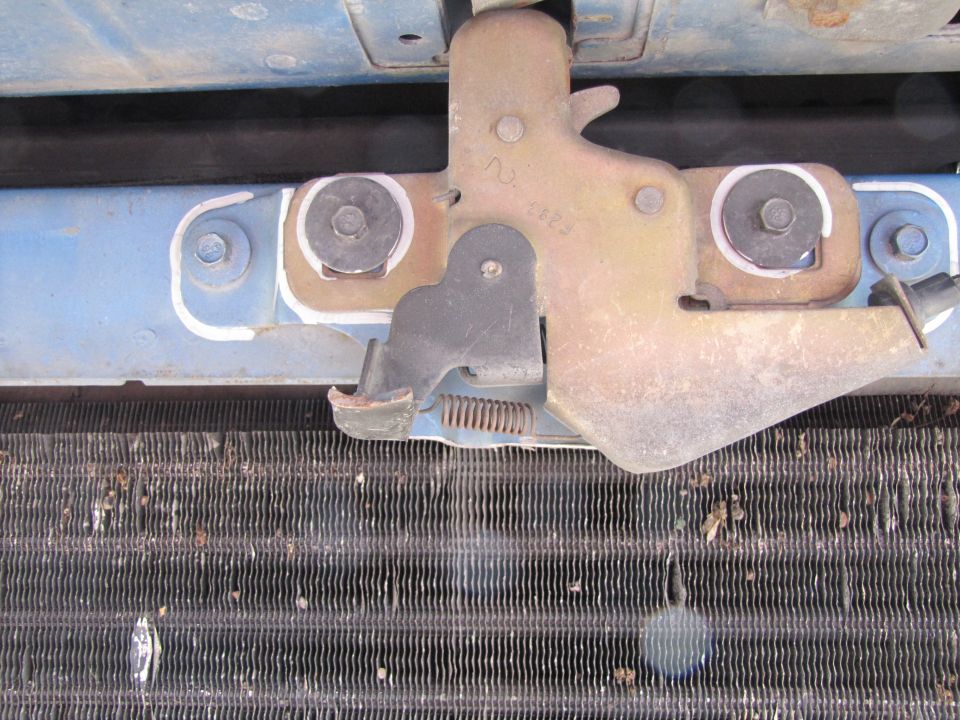 Hood latch mechanism above a dirty radiator