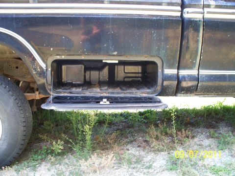 1979 Ford F-250 - The side of a black 1979 Ford F-250 pickup truck with an open storage compartment visible.