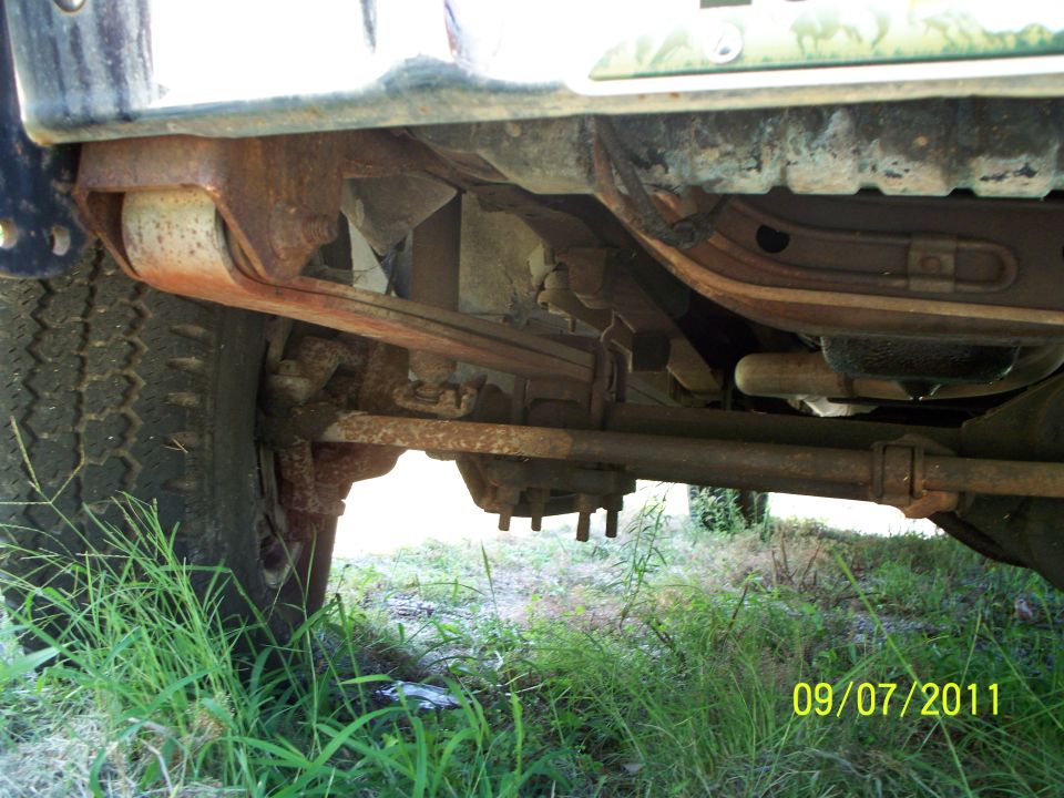 Underside view of a truck's suspension and tire, showing leaf springs and axle