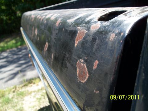 1979 Ford F-250 - The side of a truck bed shows significant rust damage and a chrome trim piece.