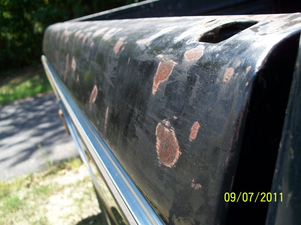 close-up of rusty black truck bed side with chrome trim