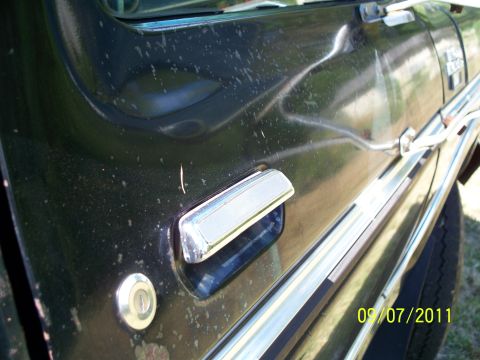 1979 Ford F-250 - A side view of a black 1979 Ford F-250 truck door, marked with dirt and damage.