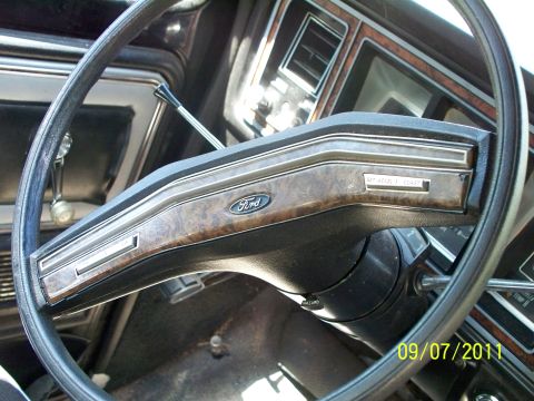 1979 Ford F-250 - The interior of a 1979 Ford F-250 shows woodgrain trim and the iconic Ford logo on the steering wheel.