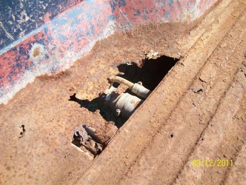 1979 Ford F-150 - The truck bed shows significant rust damage, with a hole revealing the fuel filler neck and associated components.