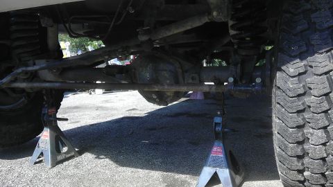1989 Ford Bronco - The vehicle's undercarriage is supported by jack stands, revealing the suspension and drivetrain components.