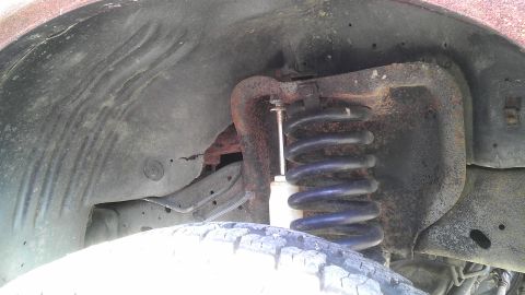 1989 Ford Bronco - Close-up view of the suspension system and tire within the wheel well of a vehicle.