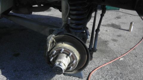 1989 Ford Bronco - Close-up of a vehicle's front wheel hub, brake rotor, and suspension system.