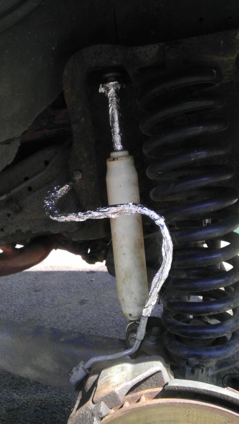 1989 Ford Bronco - Close-up view of a vehicle's suspension system, showing a shock absorber and coil spring.