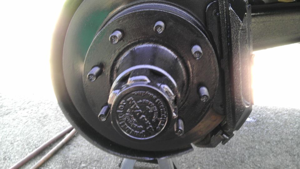 Close-up of a vehicle's front wheel hub and brake caliper assembly, painted black