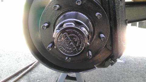 1989 Ford Bronco - A close-up view of a vehicle's wheel hub assembly, showing the brake rotor and caliper, with a hub cap embossed text and a logo.