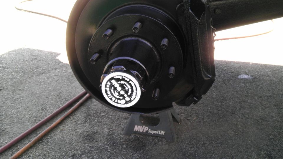 Black wheel hub with white text on a silver cap, supported by a black jack stand