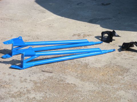 1995 Ford Bronco - These blue suspension parts are laid out on a concrete surface with a watermark for Supermotors.net.