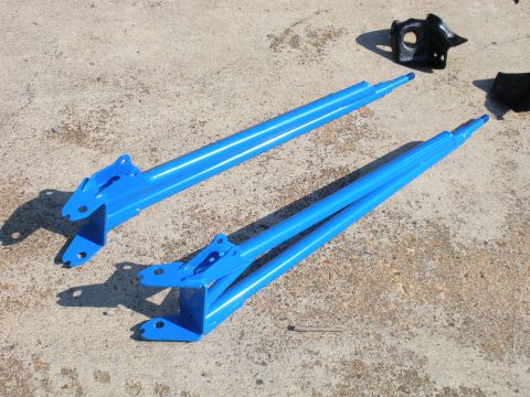 1995 Ford Bronco - Blue suspension components and a black bracket are laid out on a concrete surface.