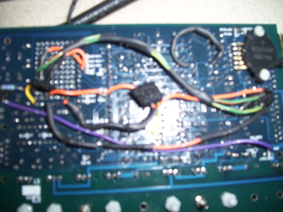 Circuit board with multiple colored wires attached, some taped