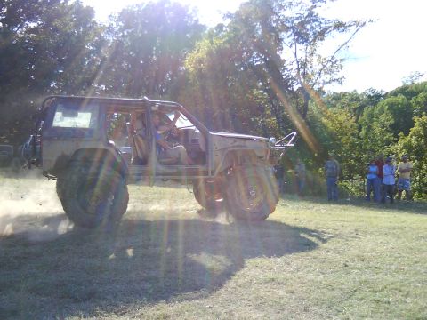 1978 Ford Bronco - Off-road vehicle with custom roll cage and large tires navigates grassy terrain.