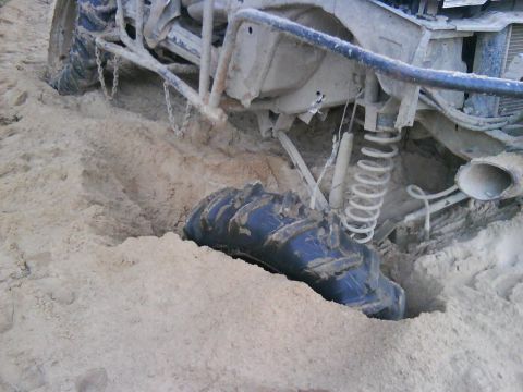 1978 Ford Bronco - A vehicle is stuck in the sand, with its tire deeply embedded.