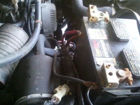 1994 Ford Bronco - Close-up view of a vehicle's engine bay, focusing on the battery and alternator components.