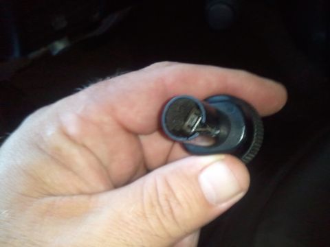 1994 Ford Bronco - A hand holds a clock spring component, likely for a vehicle's steering column.