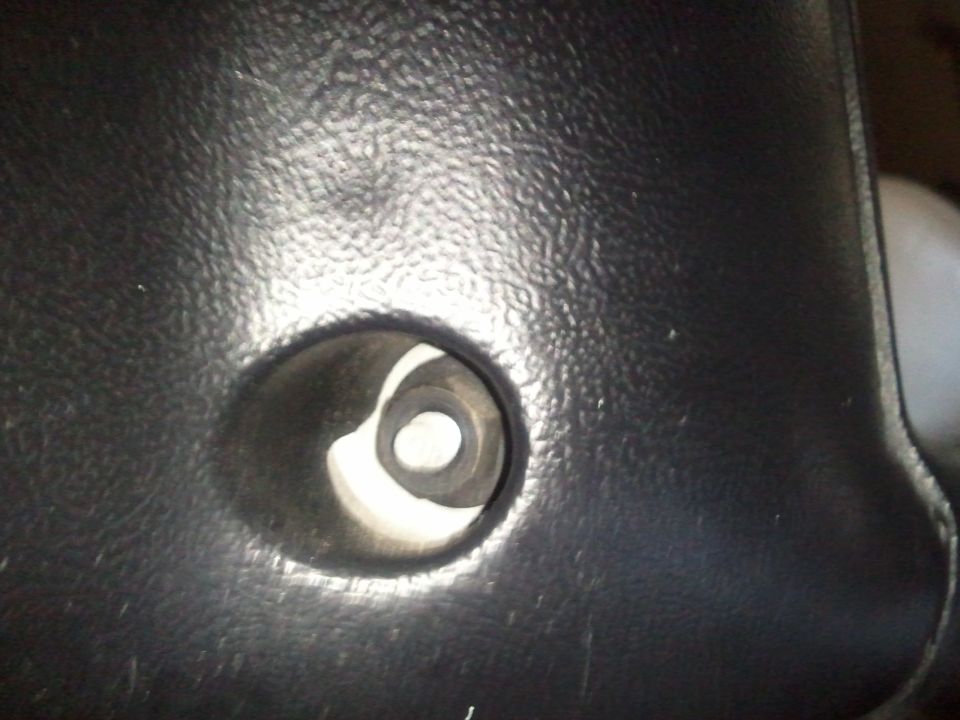 Black textured plastic steering column shroud with a circular opening revealing internal components. 1994 Ford Bronco