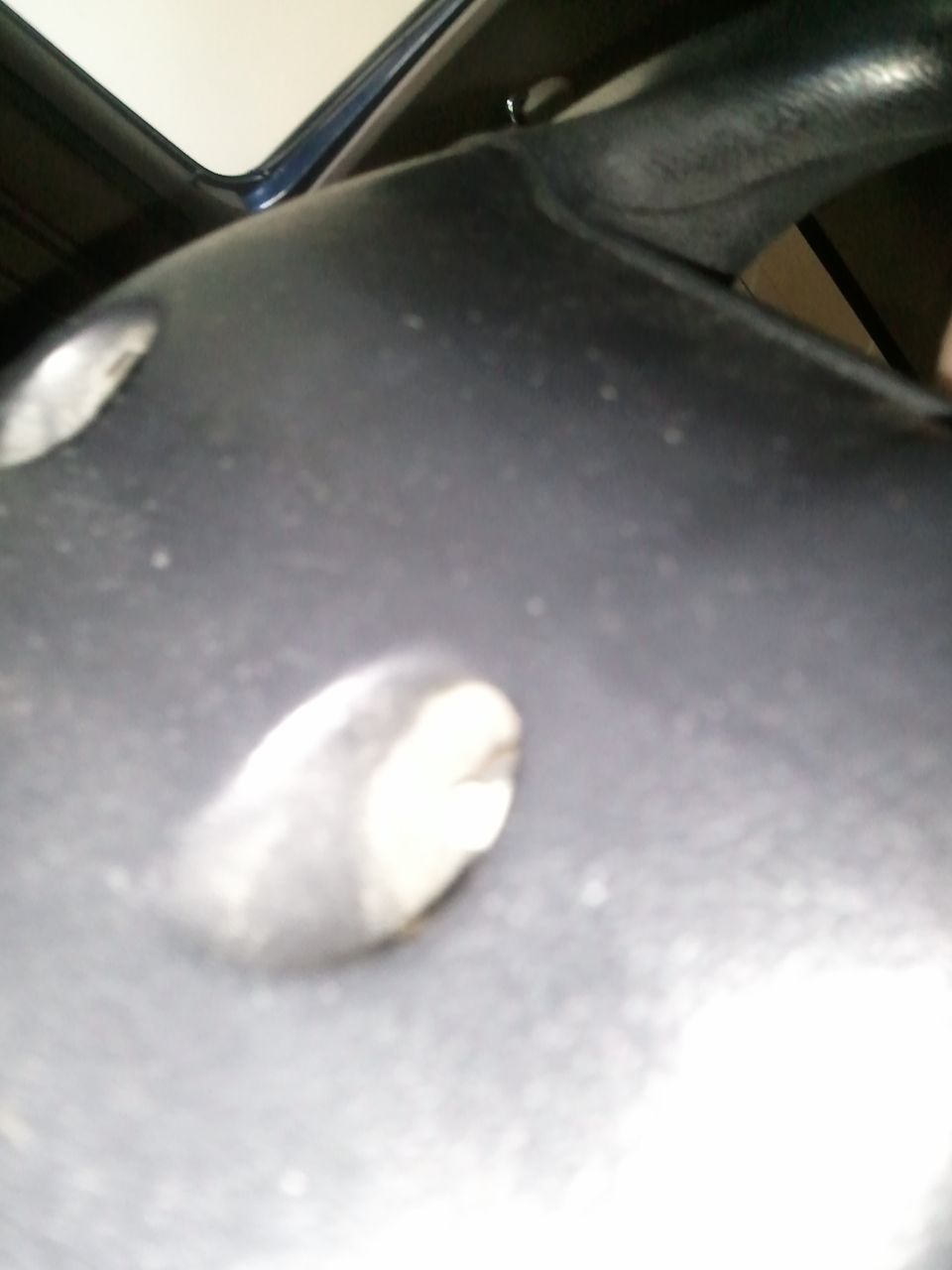 Close-up of a dark plastic steering wheel column cover with two visible mounting points