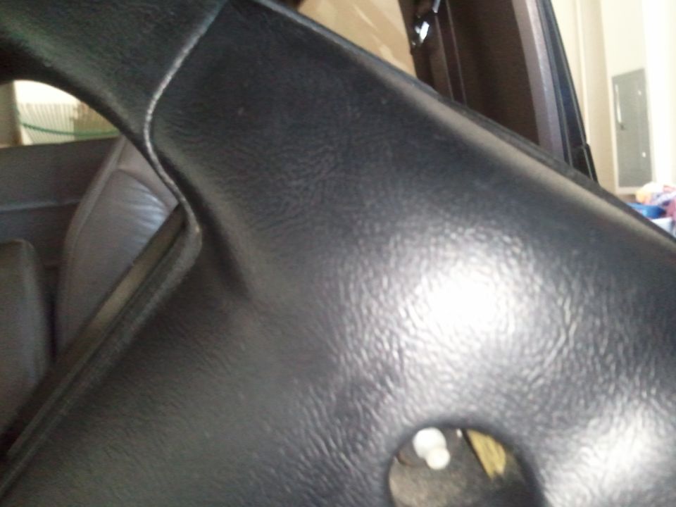 Close-up of black textured plastic trim inside a vehicle, possibly dashboard or steering column area