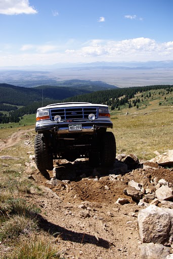 1995 Ford Bronco - White Ford Bronco navigates a challenging rocky terrain on a mountain pass.