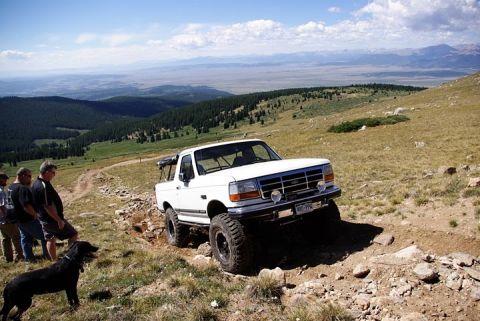 1995 Ford Bronco - A white 1995 Ford Bronco navigates a steep, rocky trail in a mountainous landscape.