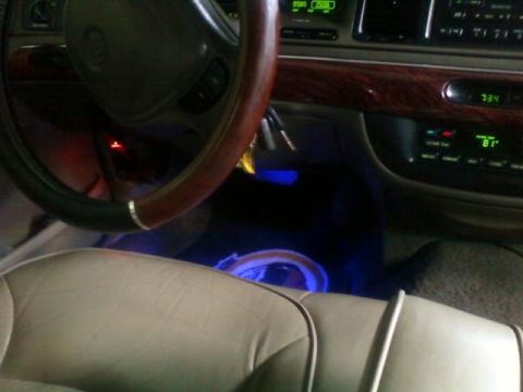 2000 Mercury Grand Marquis - The interior of a 2000 Mercury Grand Marquis features wood grain accents and custom blue lighting under the dashboard.