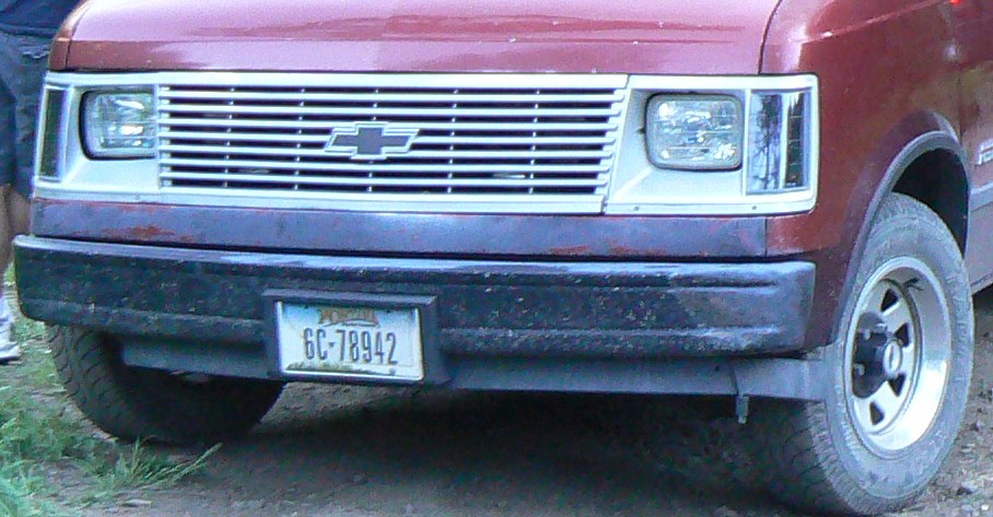 Front view of a Chevrolet van with a chrome grille and a license plate reading 6C-78942
