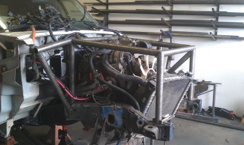 1992 Ford Ranger - The front end of a 1992 Ford Ranger is visible, a custom roll cage and exposed engine.