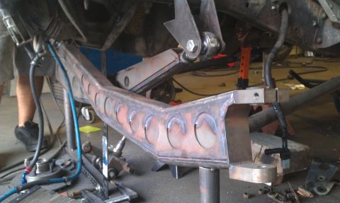 1992 Ford Ranger - Close-up of a custom-welded suspension part with circular cutouts, undergoing modification in a workshop.