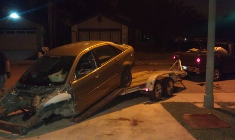 1992 Ford Ranger - A gold sedan, stripped of its front end, is loaded onto a trailer and towed by a dark pickup truck at night.
