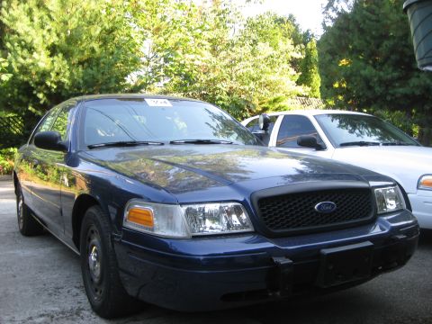 2003 Ford Crown Victoria - A blue 2003 Ford Crown Victoria is parked in front of another Crown Victoria.