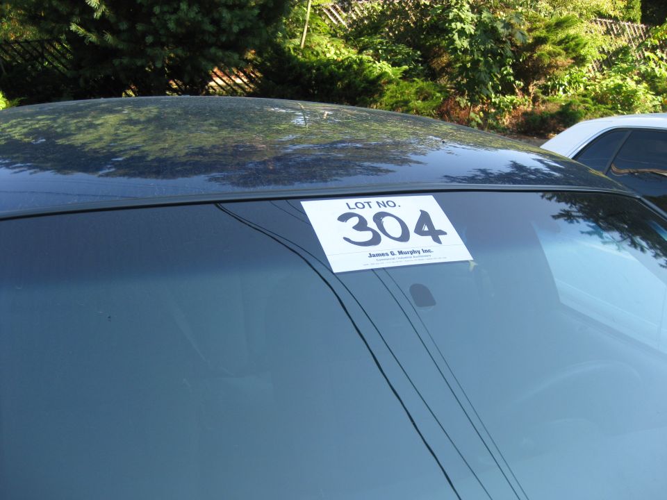 Car windshield with a "LOT NO. 304" sticker and "James G. Murphy Inc." text below it. Another car is visible to the right