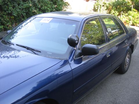 2003 Ford Crown Victoria - Front quarter view of a blue 2003 Ford Crown Victoria sedan with a paper tag on the windshield.