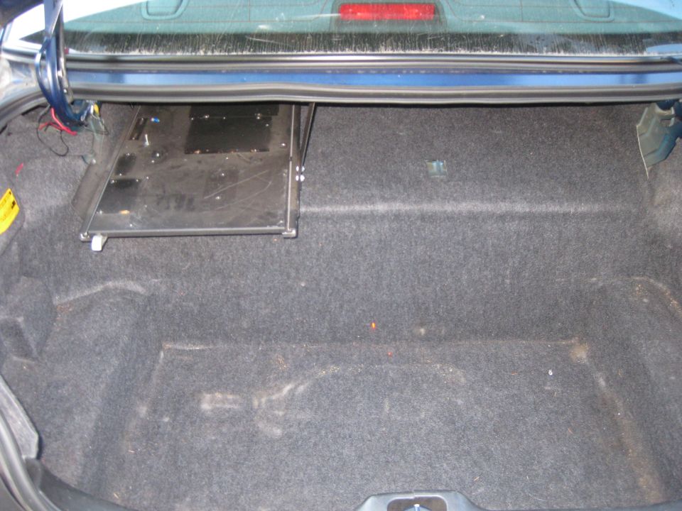 Car trunk with carpet lining and a metal tray mounted on the side
