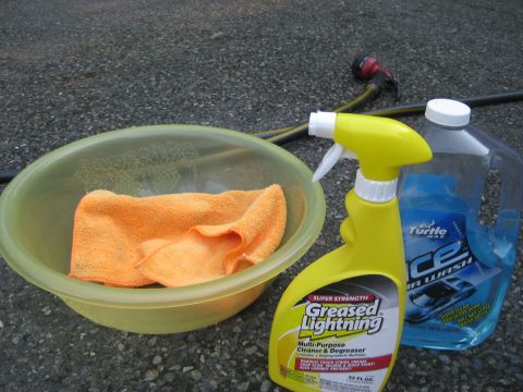 2003 Ford Crown Victoria - Supplies for washing a car: a bowl with a towel, spray cleaner, and car wash soap.