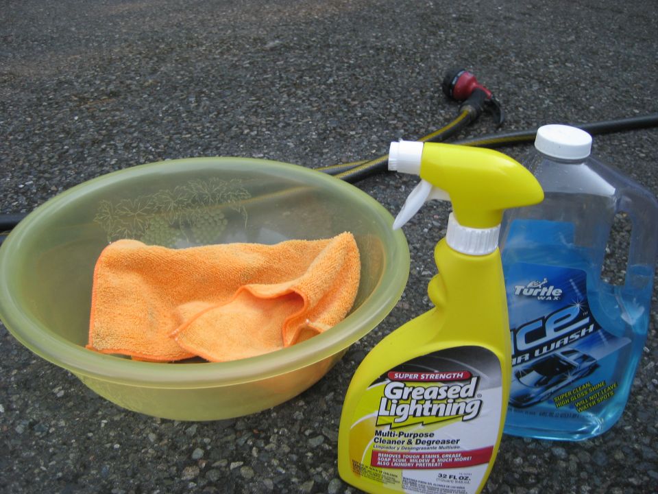 Orange microfiber towel in a yellow bowl next to Greased Lightning cleaner and Turtle Wax Ice car wash soap