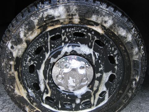 2003 Ford Crown Victoria - A truck wheel and tire are covered in soap suds, with a chrome hubcap visible in the center.