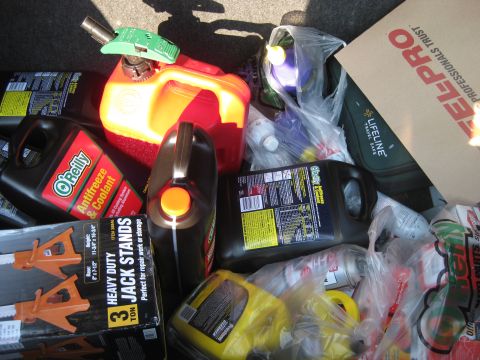 2003 Ford Crown Victoria - A collection of automotive fluids and tools are packed into the trunk of a vehicle.