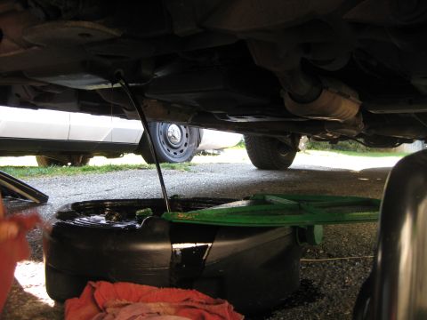 2003 Ford Crown Victoria - Oil change in progress with a catch pan positioned beneath the vehicle's drain plug.