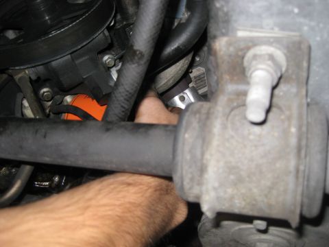 2003 Ford Crown Victoria - Close-up view of an engine component with a hand reaching into the engine bay.