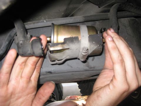 2003 Ford Crown Victoria - Hands are shown replacing a vehicle's fuel filter, a common maintenance task.