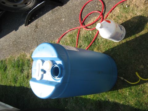 2003 Ford Crown Victoria - A blue barrel, a red hose, a white jug, and a yellow hose are laid out on grass and asphalt.