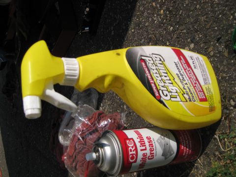 2003 Ford Crown Victoria - Cleaning supplies, including a spray bottle and grease, are laid out on a paved surface.
