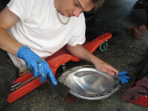 2003 Ford Crown Victoria - A person cleans a differential cover with a scraper, wearing blue gloves.