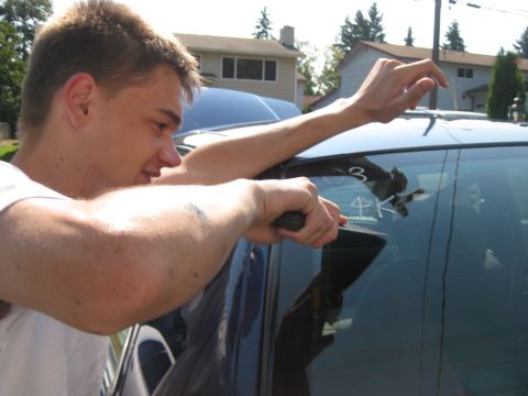 2003 Ford Crown Victoria - Person cleaning a car window with a squeegee, revealing markings on the glass.