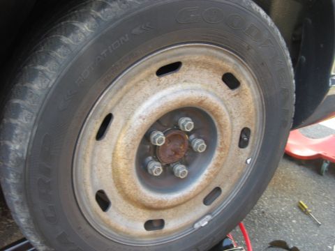 2003 Ford Crown Victoria - Close-up of a worn steel wheel and tire, showing rust and a Goodyear tire tread.