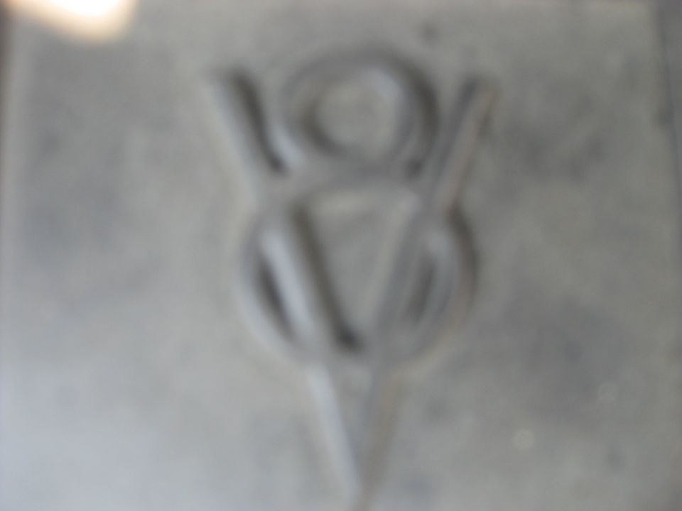 Embossed V8 emblem on a gray, textured surface