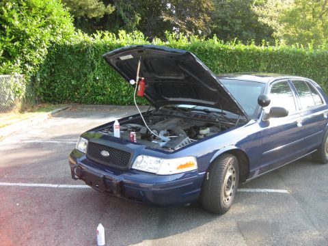 2003 Ford Crown Victoria - A blue 2003 Ford Crown Victoria is parked outside with its hood open, undergoing some maintenance.